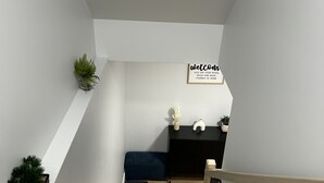 A modern staircase with a wooden finish, a black mat at the bottom, and a dark blue bench. A welcome sign is visible on the wall. - Charming 1-bedroom apartment in enchanting Moncton with WiFi (Moncton)
