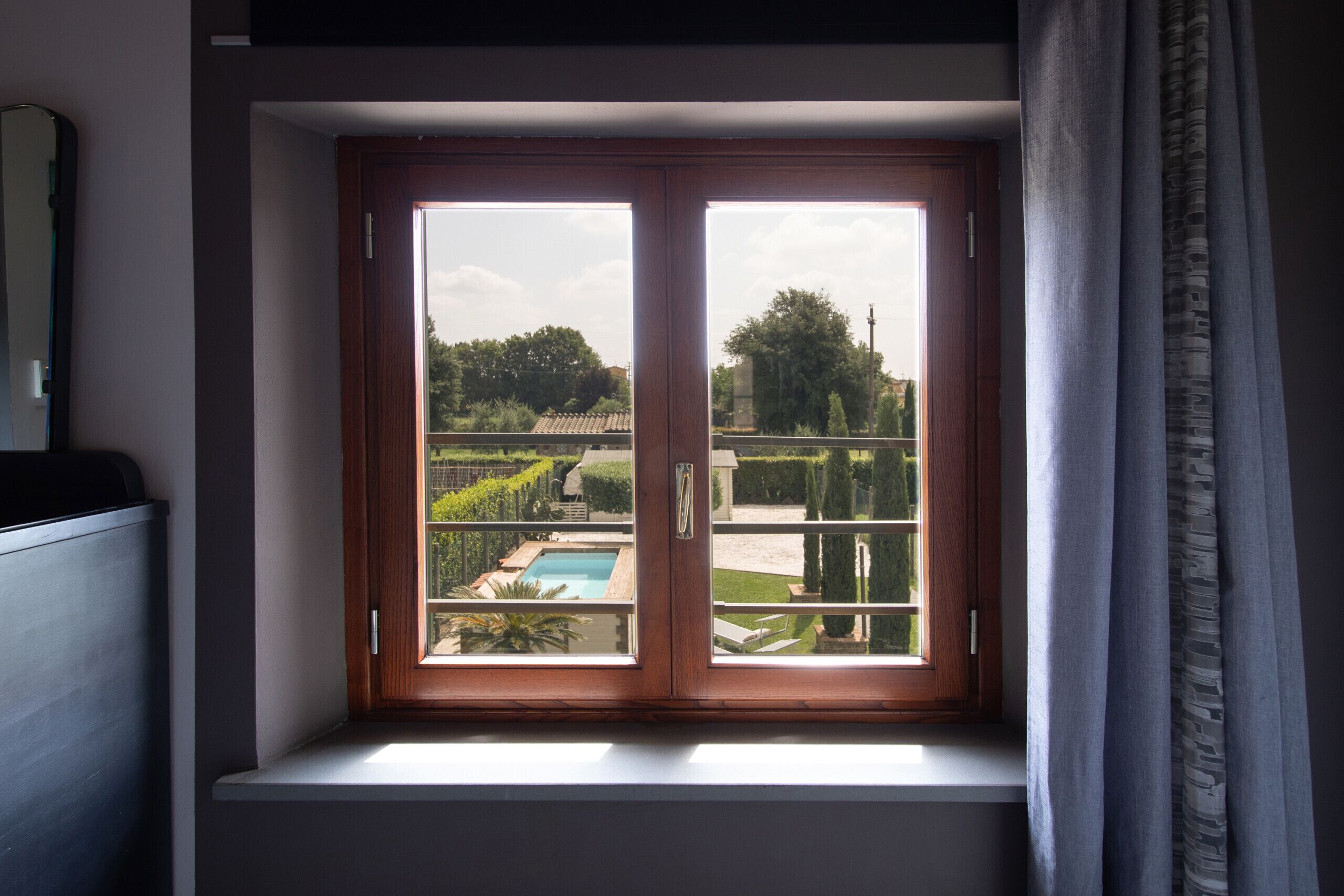 A window with a view of a swimming pool and garden.