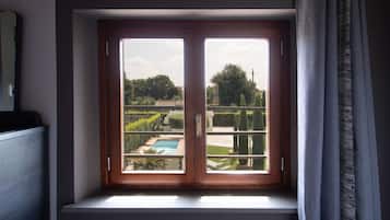 A window with a view of a swimming pool and garden.