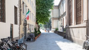 A paved street lined with parked bicycles and a row of buildings with large windows and balconies. - Dimora San Paolino in Center Town (Lucca)