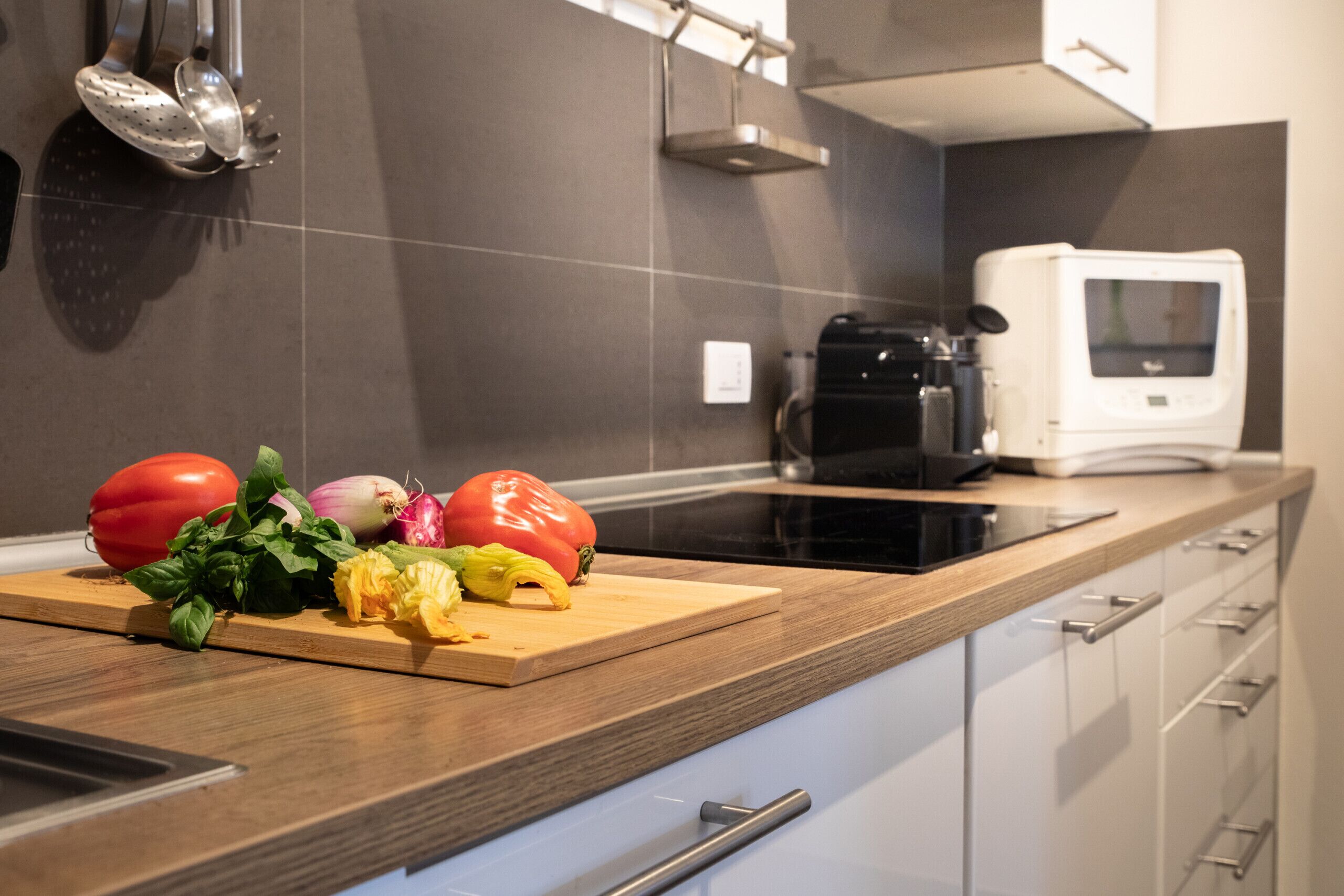 A modern kitchen with a wooden countertop, a microwave, and a coffee maker.