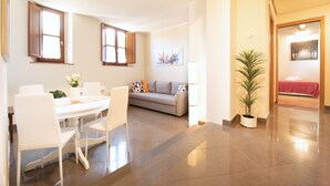 A modern living room with a dining area, a grey sofa, and a potted plant. - Dimora San Paolino in Center Town (Lucca)