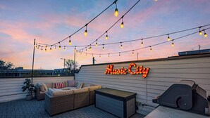 An outdoor patio area with string lights, a sofa, a grill, and a neon sign reading "Music City". - Weekend getaway: 2 rooftop homes, sleeps 24, near Broadway, Nashville (Nashville)