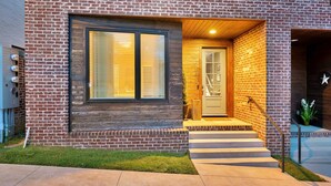 A modern house with a brick exterior, a wooden front door, and a small front porch with steps leading to the door. - Weekend getaway: 2 rooftop homes, sleeps 24, near Broadway, Nashville (Nashville)