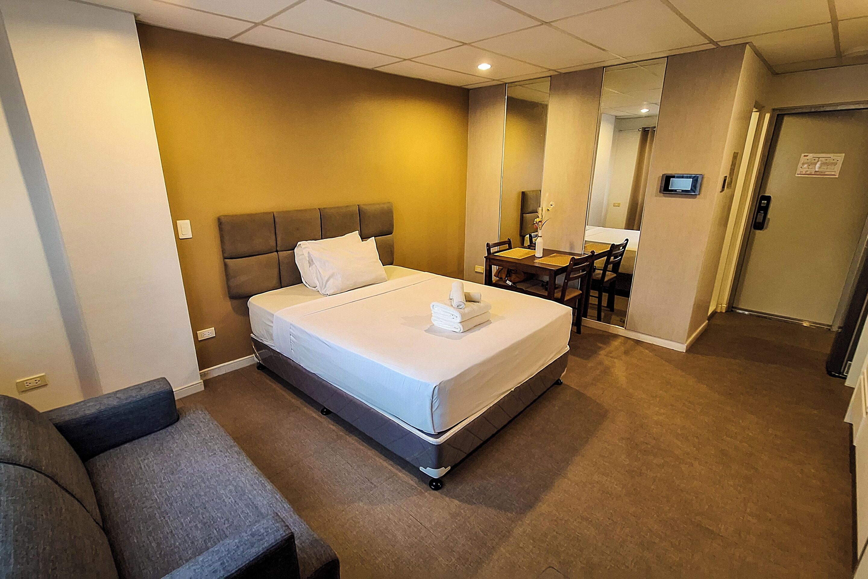 Une chambre d’hôtel avec un lit, un bureau, une chaise et un miroir.