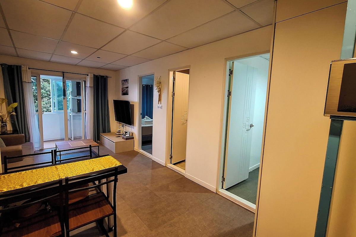 Un salon moderne comprenant un coin repas, un téléviseur à écran plat et une porte-fenêtre coulissante donnant sur un balcon.