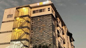 Een modern gebouw met een 'smart' bord aan de bovenkant, met een gevel van glas en steen en een opvallende vluchttrap.