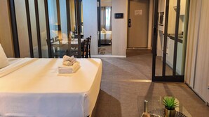 Een hotelkamer met een bed, een bureau en een stoel. Er is een deur die naar een andere kamer leidt.