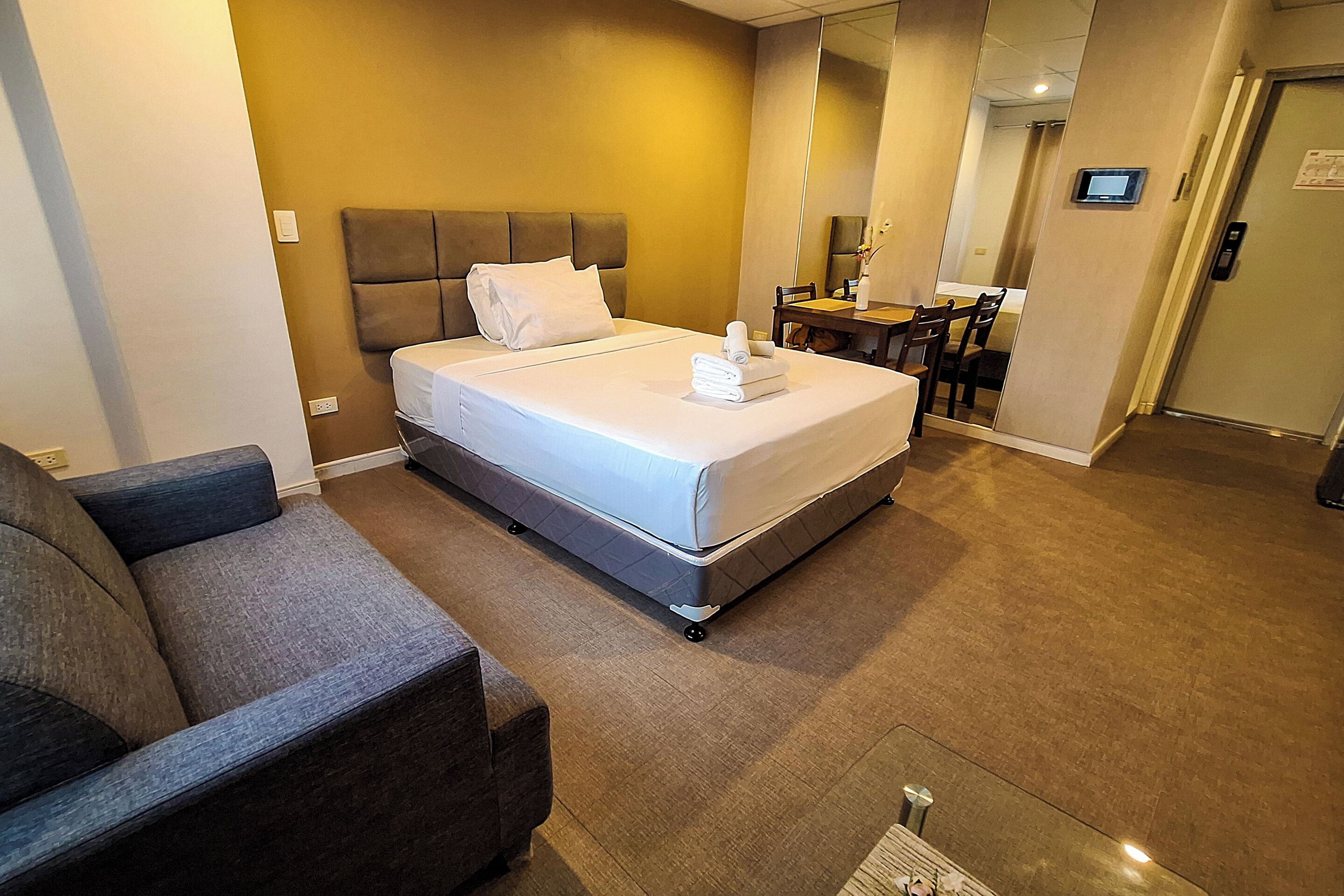 A hotel room with a bed, a sofa, a desk, and a chair.