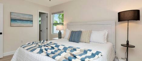 Un dormitorio con cama, ventilador de techo, lámpara y un cuadro en la pared.
