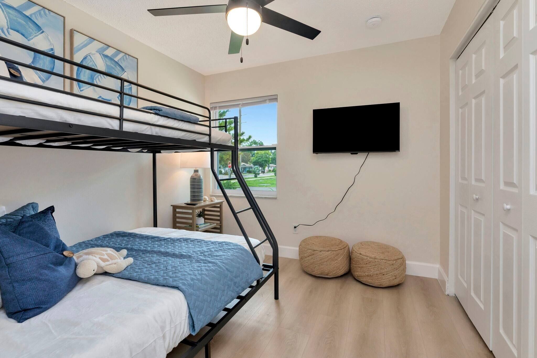 Een slaapkamer met stapelbedden, een plafondventilator, een televisie en een raam met uitzicht.