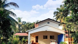 Una casa a un piano con un portico coperto, immersa nella vegetazione tropicale.
