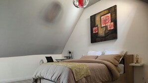 Un dormitorio moderno con cama, mesita de noche, lámpara y un cuadro en la pared.