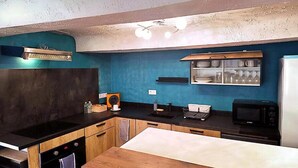 Una cocina moderna con encimera negra, armarios de madera, microondas y refrigerador.