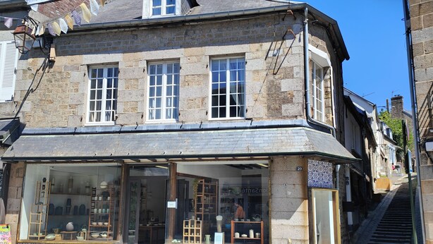 Un edificio de piedra tradicional con una tienda en la planta baja que exhibe cerámica.