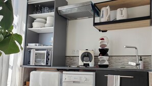 A compact kitchen with a microwave, toaster, and a coffee machine on the countertop.