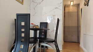A dining area with a marble wall, a table with chairs, and a door in the background.