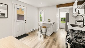 Une cuisine moderne avec des meubles blancs, une cuisinière encastrée et une fenêtre donnant sur le jardin.