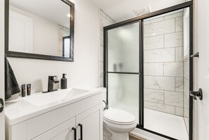 Een badkamer met een witte wastafel, een grote spiegel, een toilet en een douchecabine met glazen wanden.