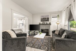 Un salon moderne avec une cheminée, deux canapés gris, une table basse et un téléviseur.