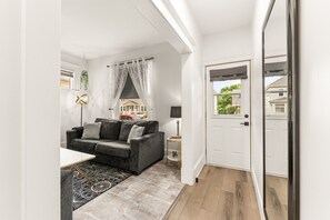Een moderne woonkamer met een grijze bank, een bijzettafeltje en een kamerkleed met dessin.