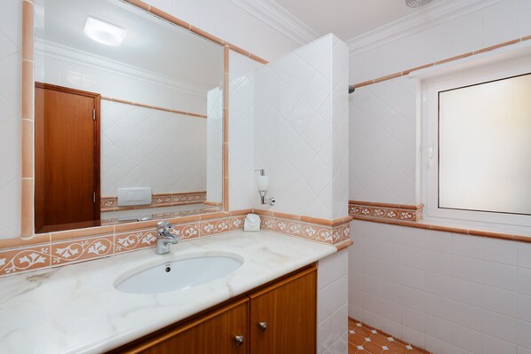A bathroom with a white sink, wooden cabinet, and a large mirror. - Casa Waldemar, luxury villa in Ferragudo with panoramic sea views (Ferragudo)