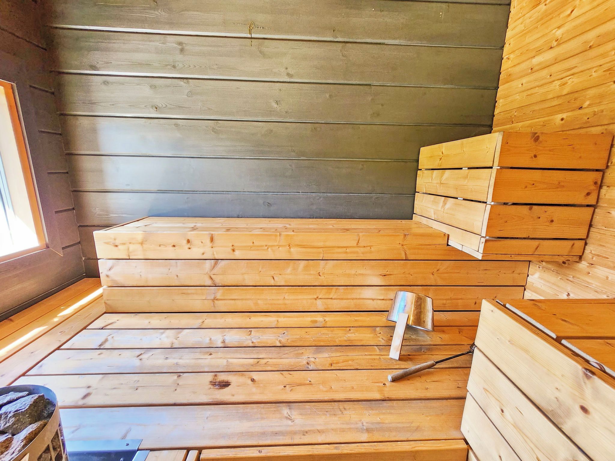 Un sauna con bancos de madera y un banco de metal.