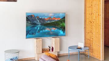 A living room with a flat-screen TV mounted on the wall, a sofa, a small round table, and a wooden cabinet.
