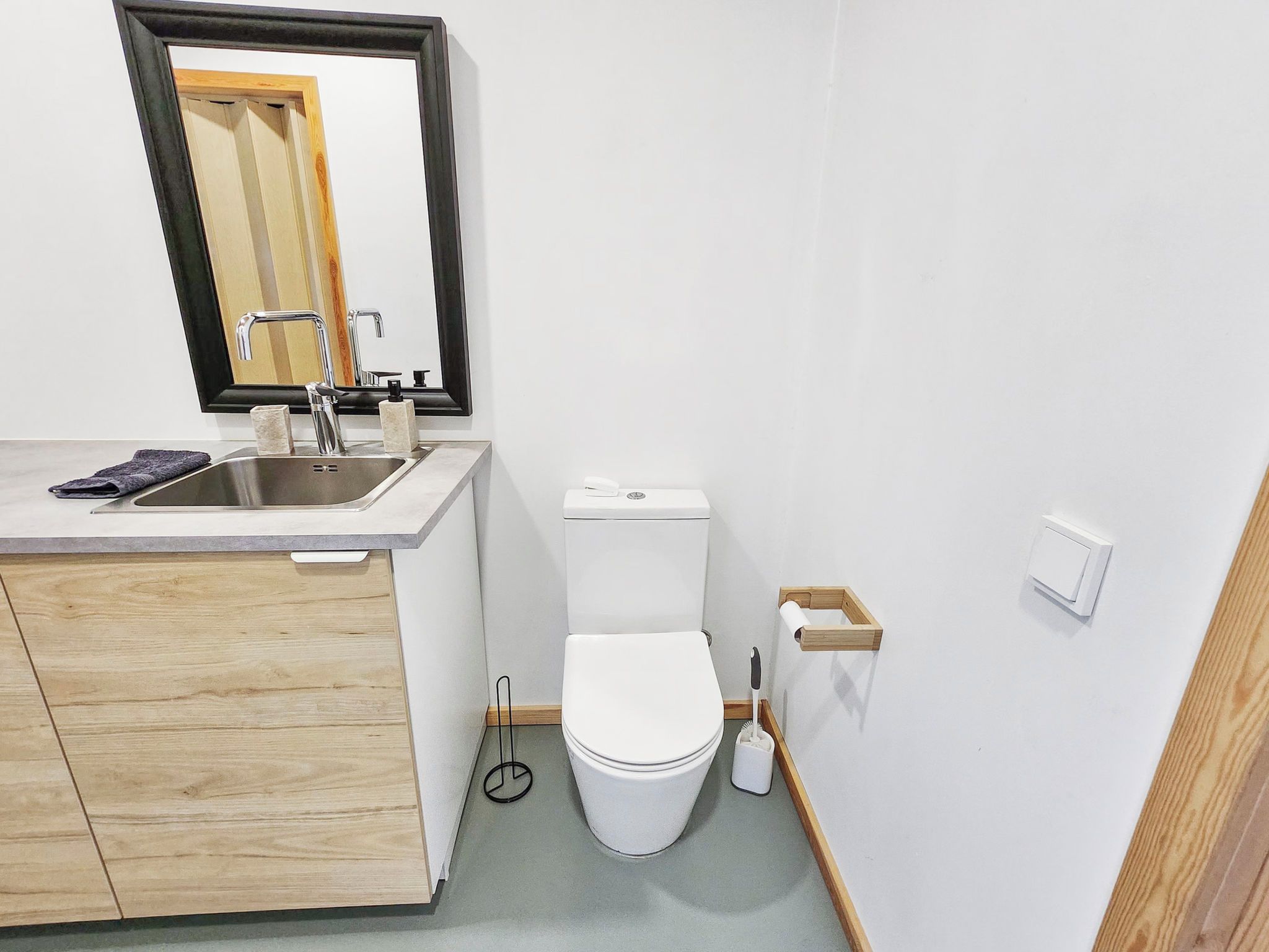 Een moderne badkamer met een wastafel, spiegel, toilet en een houten kastje.