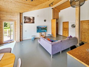 Un intérieur moderne avec un canapé, une table à manger et un téléviseur fixé au mur.
