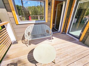 A wooden deck with a white metal chair and a small round table.