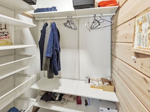 Un dressing ouvert avec des étagères, une tringle pour suspendre les vêtements et un mur en bois.