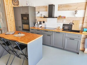 A modern kitchen with grey cabinets, a wooden countertop, and a built-in oven.