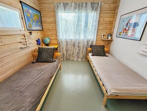 A room with two wooden beds, a globe, a map, and a window with curtains.