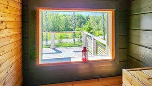 Une cabane avec une petite fenêtre donnant sur une terrasse et une forêt.