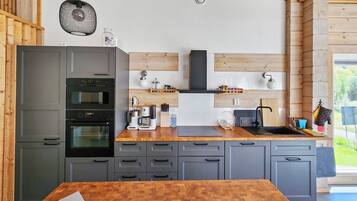 Eine moderne Küche mit grauen Schränken, einer Holz Arbeitsplatte und einem eingebauten Backofen.