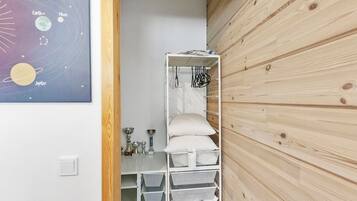Ein Schlafzimmer mit einer Holzwand, einem Bett mit weißer Bettwäsche, einem Regal mit Dekoration und einem Poster vom Sonnensystem.