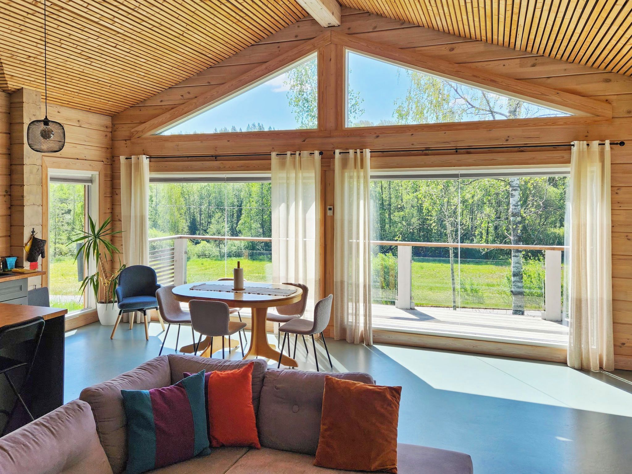Une pièce spacieuse avec un plafond haut, de grandes fenêtres, un coin repas et un espace détente avec un canapé.