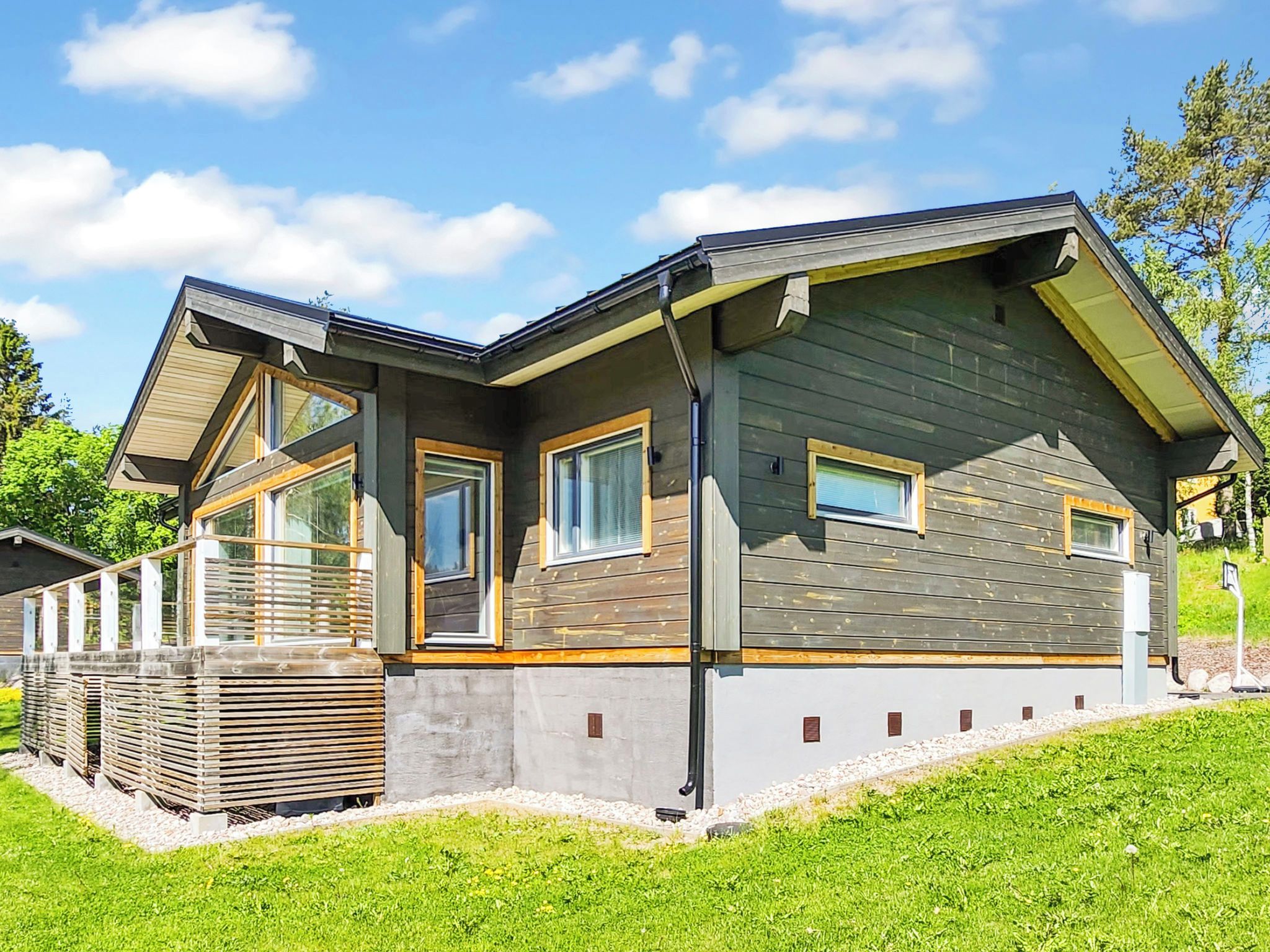 A modern house with a sloped roof, large windows, and a well-maintained lawn.