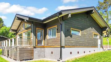 A modern house with a sloped roof, large windows, and a well-maintained lawn.
