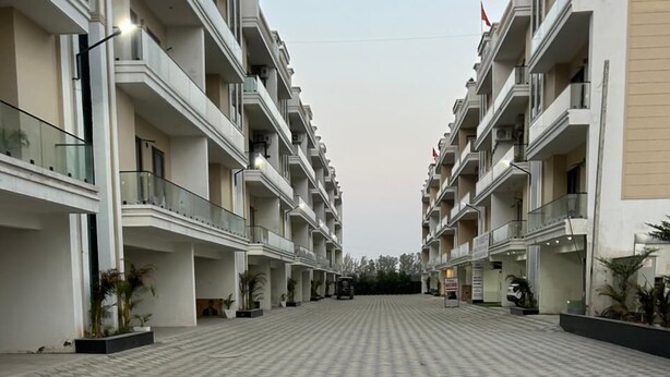 A spacious, open-plan hotel lobby with a checkered floor pattern, multiple balconies, and potted plants. - Aerostays Mohali (Dera Bassi)