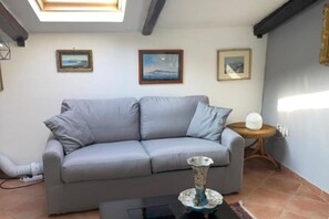 En stue med en grå sofa, et lille rundt bord og en vase på sofabordet.