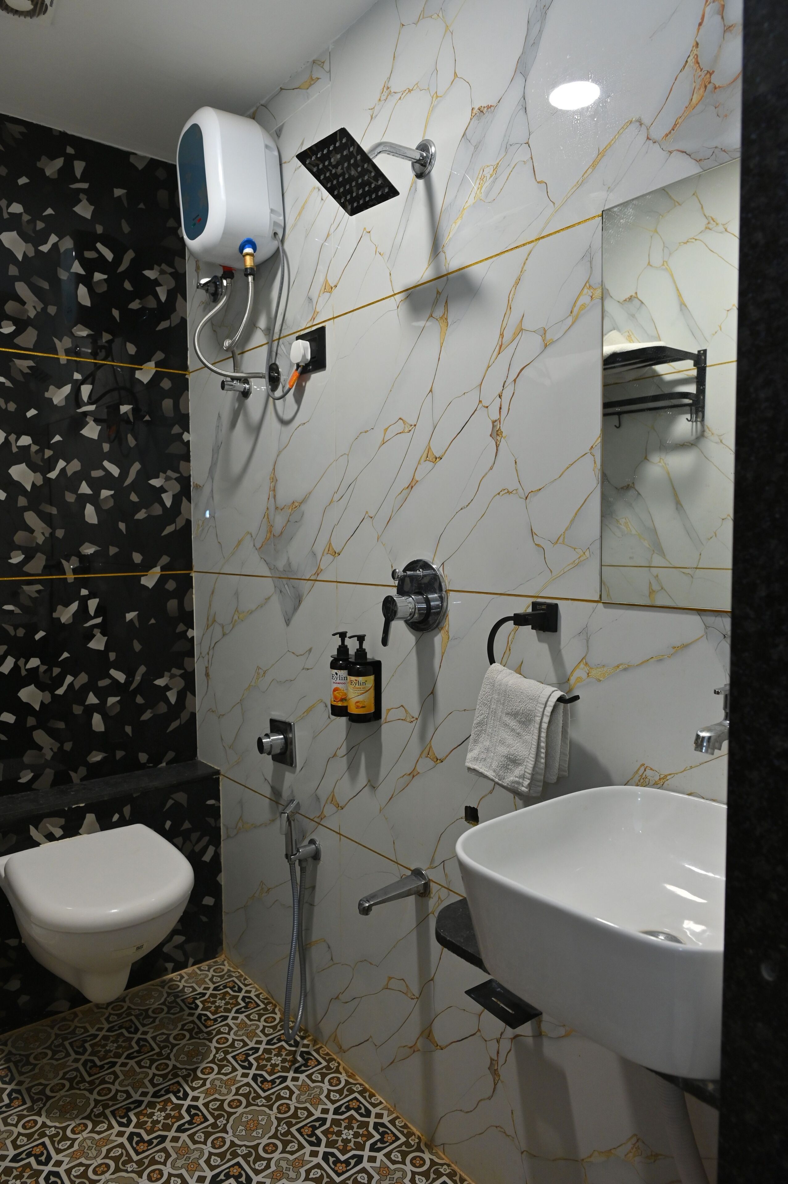 A bathroom with a toilet, a sink, a handheld showerhead, and a towel rack.
