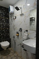 Une salle de bain comprenant des toilettes, un lavabo, une douchette à main et un porte-serviettes.