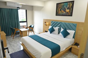 Camera d'albergo con un letto, una scrivania, una sedia, un comodino, una lampada a muro e un quadro.