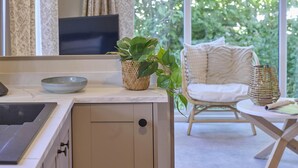 Een keuken met een spoelbak, een kom, een geweven mand met een plant en een stoel met kussens.