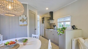 Een moderne keuken met witte kasten, een ronde eettafel en een hanglamp.