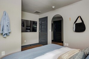 Un dormitorio con cama, espejo, puerta y bolso colgado.