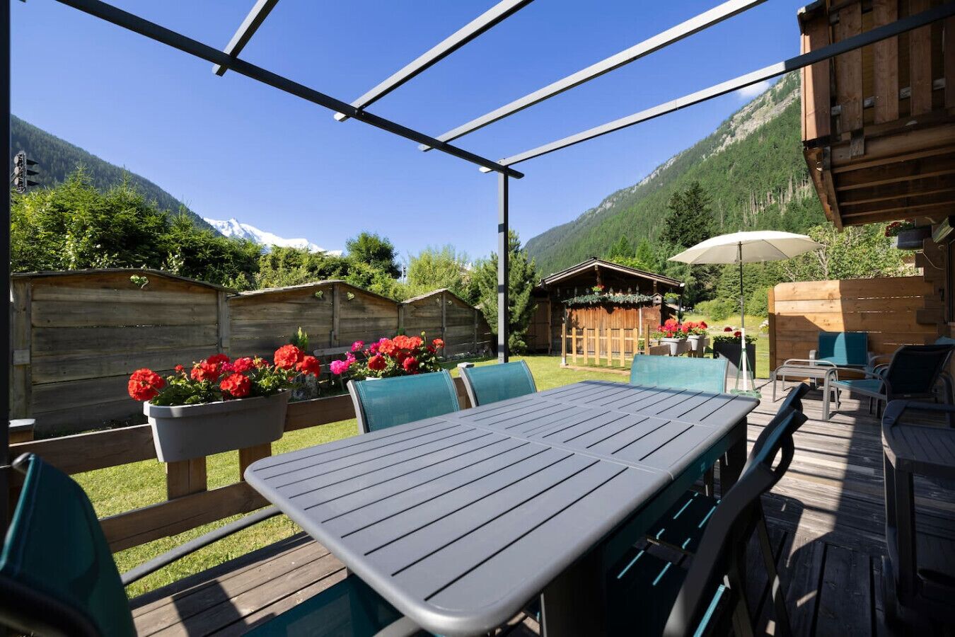 An outdoor patio with a table and chairs, surrounded by wooden fences and potted plants.
