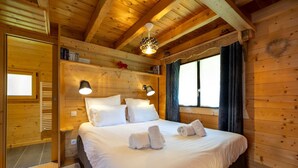 Un dormitorio de cabaña de madera con una cama, dos lámparas de noche y una ventana con cortinas.